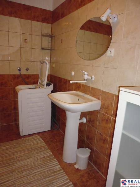 Bathroom with brown tiles, a sink, and a washing machine in a 2-room apartment.