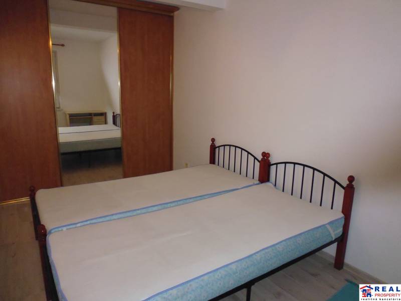 Double bed, wardrobe with mirror, and wooden decor flooring in a 2-room apartment.