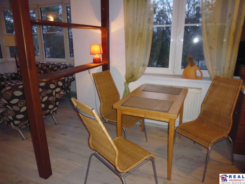 Dining area with a table and wicker chairs, floor with wooden decor.