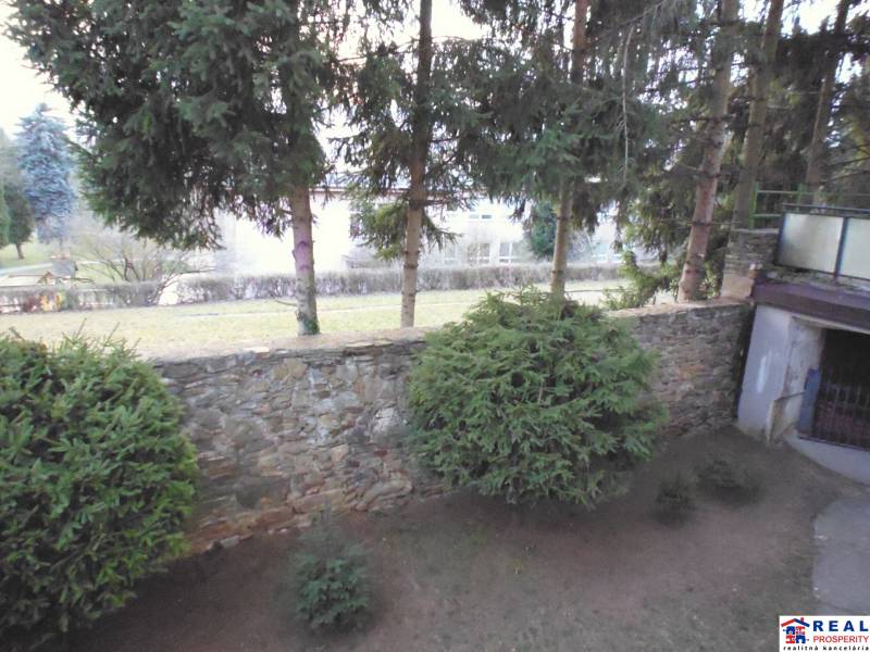 A garden with conifers and a stone wall near a 2-room apartment on Veselá Street in Prešov.