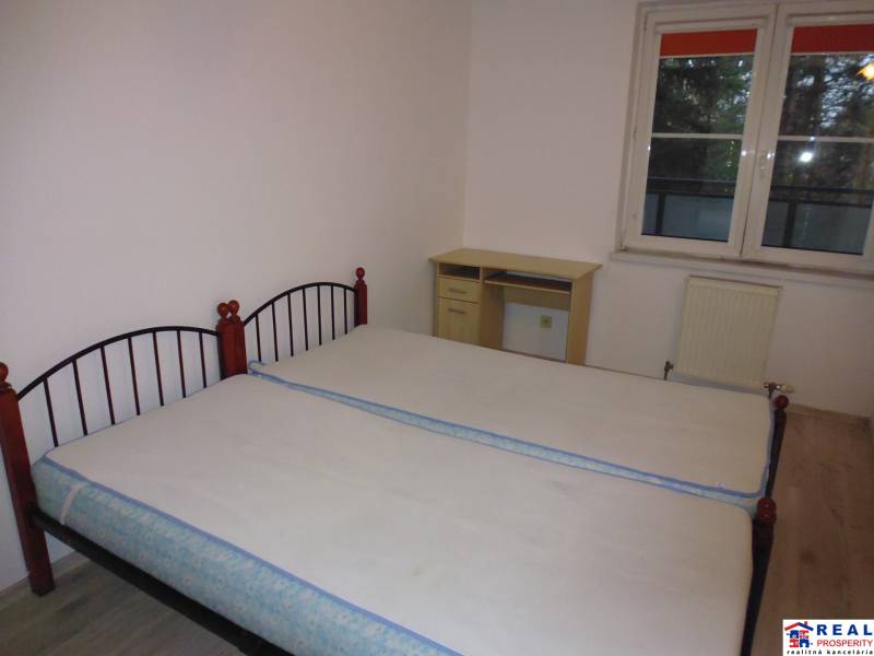 Bedroom in a 2-room apartment with two beds and a window, floor with wood decor.