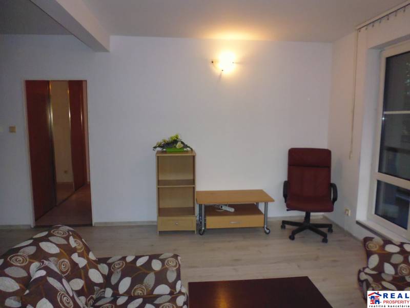 Living room in a two-room apartment with a wooden decor floor and a comfortable armchair.