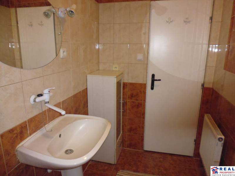A bathroom with a sink and a mirror in a 2-room apartment, tiles in earthy colors.