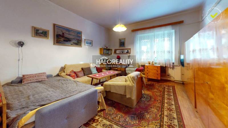 Living room in a family house with comfortable seating, decorative rugs, and a light-colored wall.