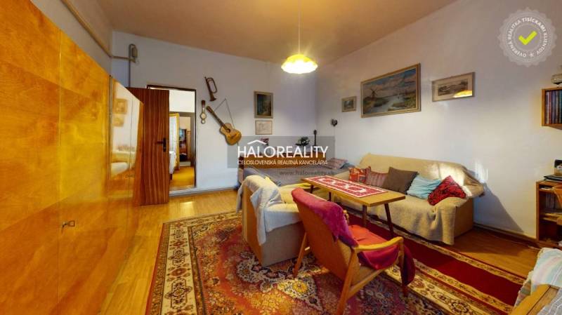 Living room with a sofa and armchairs, family house with wood-patterned flooring.