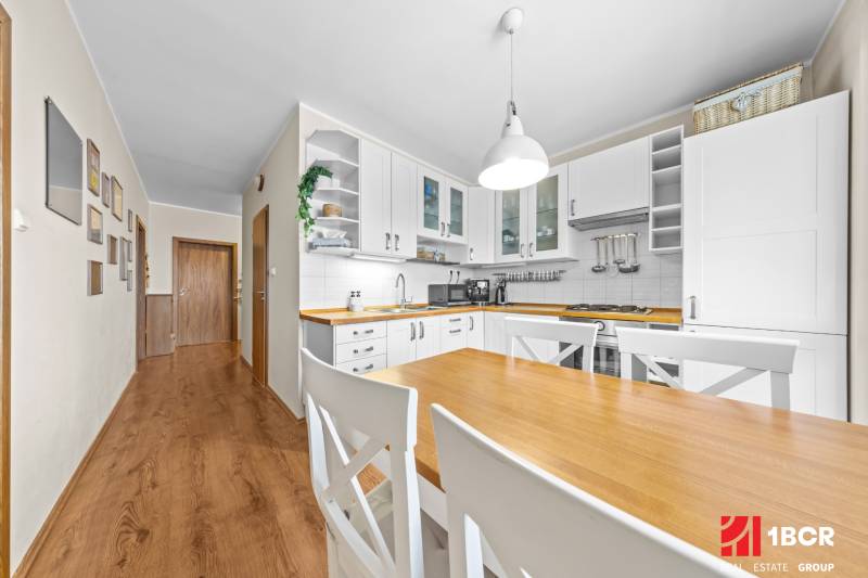A bright kitchen in a 3-room apartment with a wooden table and a floor with a wooden decor.