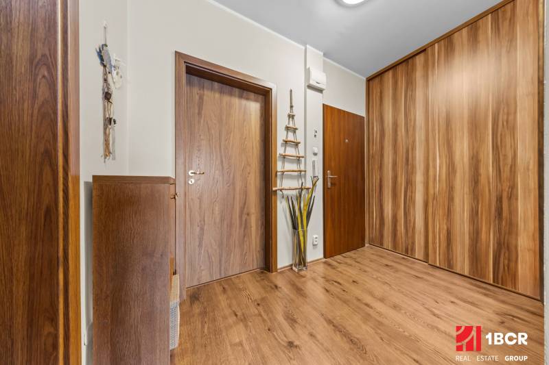 A hallway with a wooden decor floor in a 3-room apartment, built-in wardrobes and decorations.