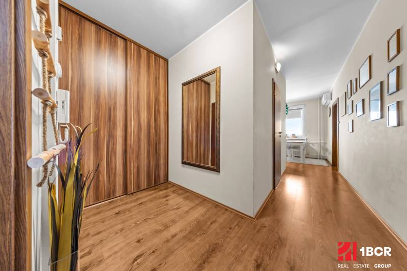 A hallway in a 3-room apartment with a wooden decor floor, a mirror, and storage space.