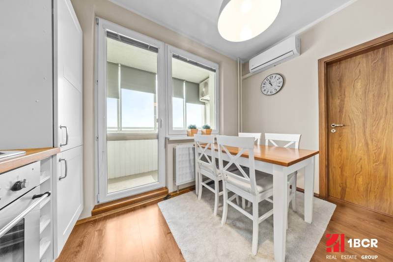 Dining area in a 3-room apartment with a wood-patterned floor and white furniture.