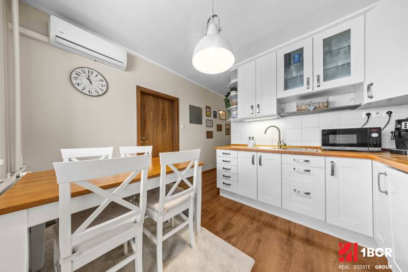 A kitchen in a 3-room apartment with white cabinets and a wooden decor floor.