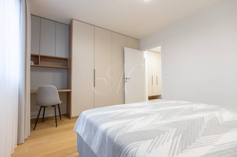 A bright bedroom with a desk, wardrobe, and bed in a 2-room apartment.
