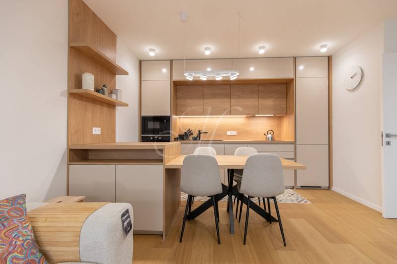 A kitchen in a 2-room apartment with a dining table and a floor with a wooden decor.