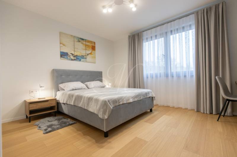 Bedroom in a two-room apartment with a wood-patterned floor and a gray bed.