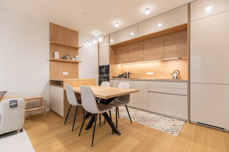 A kitchen in a 2-room apartment with modern furniture and a wooden decor floor.