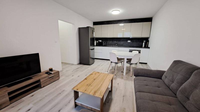 Living room with kitchen in a family house, wooden decor flooring, light furnishings.