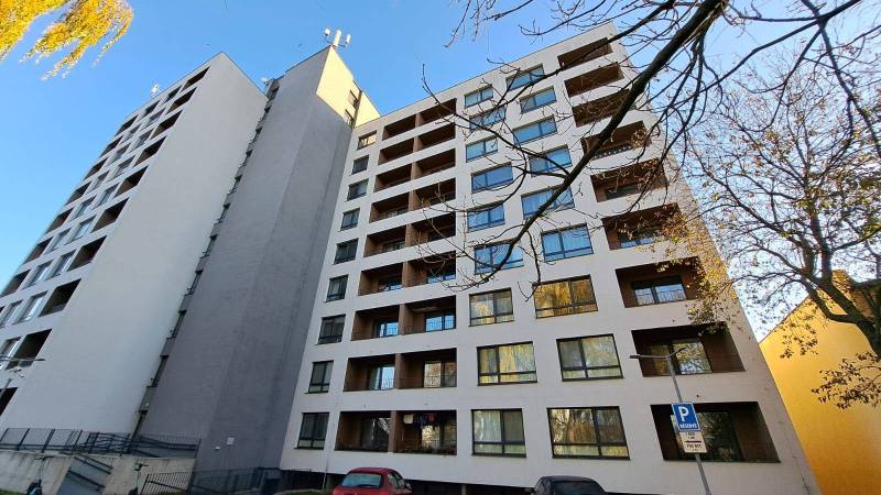 High-rise residential building in Poprad with a parking lot and trees in the surroundings.
