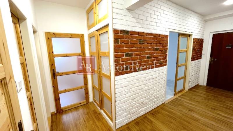 Interior of a 3-room apartment with a wooden decor floor and brick cladding.