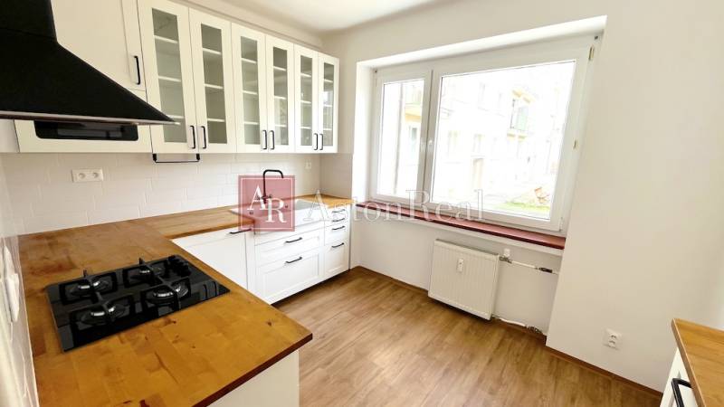 A kitchen in a 3-room apartment with white cabinets and a wood-patterned floor.