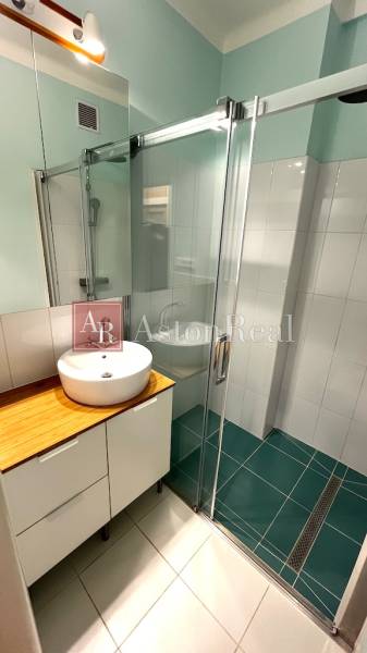 Bathroom with a shower and a sink on a wooden decor in a 3-room apartment.