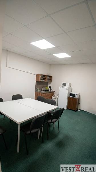 Dining room in offices with a white table, chairs, and kitchen equipment.
