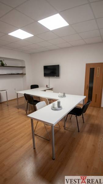 Offices with white desks, black chairs, and wood-patterned flooring.