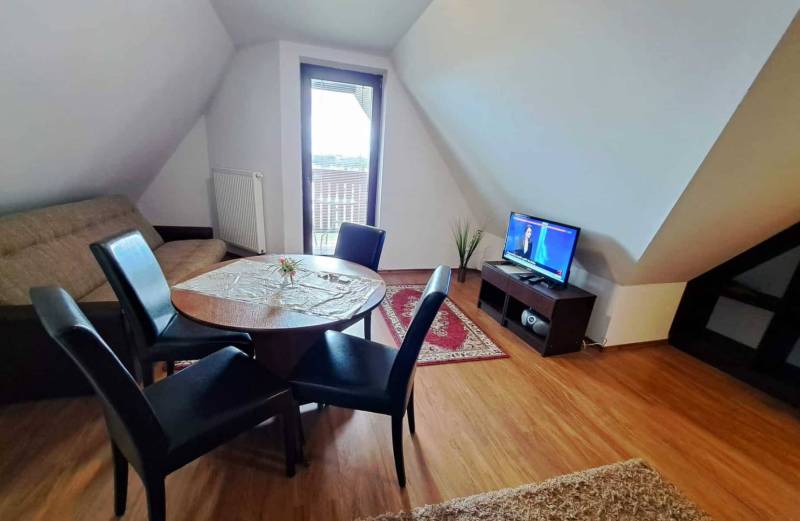 A living room in a three-room apartment with a wooden decor floor and a dining table.