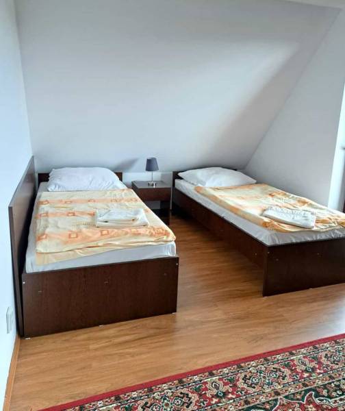 A bedroom with two single beds, a nightstand, and a wooden-patterned floor in a three-room apartment.