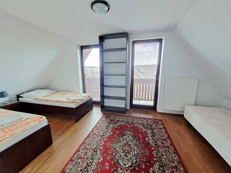 A bedroom in a 3-room apartment with two beds, a carpet, and a wooden decor floor.