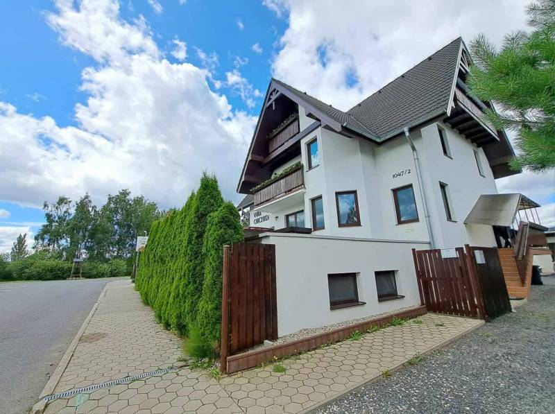 A family house surrounded by green thuja trees on the street of Veľká Lomnica.