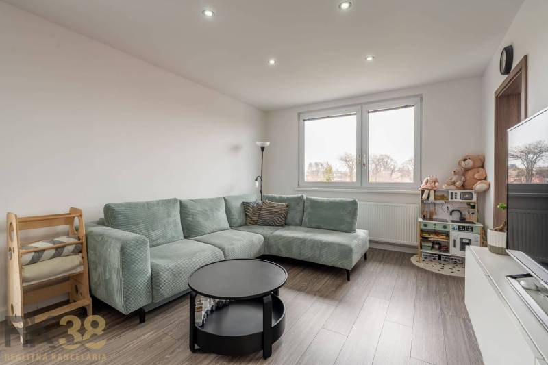 Living room with a corner sofa and a wooden decor floor in a 4-room apartment.