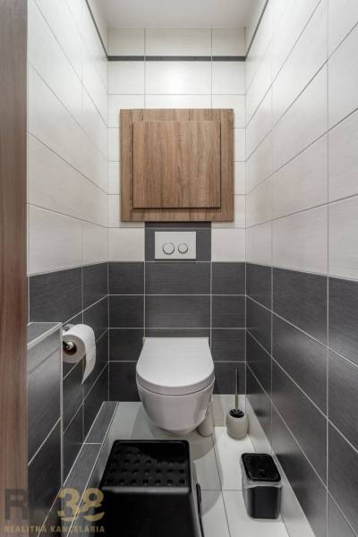 A bathroom with white and gray tiles, wooden decor cabinet, 4-room apartment.