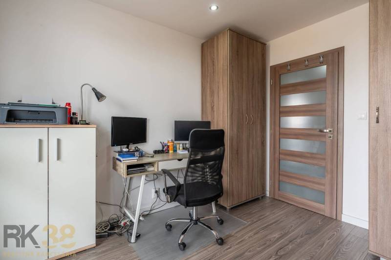 A workspace in a 4-room apartment with a wooden decor floor and office equipment.