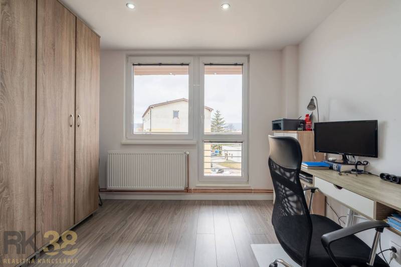 A study room in a 4-room apartment with a wooden decor floor and a large window.
