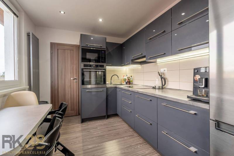 A kitchen in a 4-room apartment with a wood-patterned floor and modern furniture.
