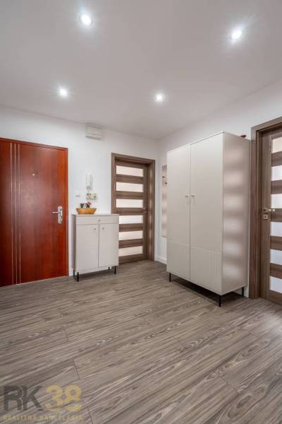 Entrance hallway with a wardrobe and a cabinet, floor with wooden decor in a 4-room apartment.