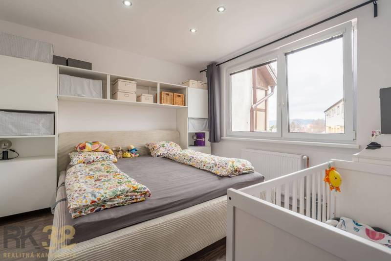 Bedroom in a 4-room apartment with a bed, storage space, and a baby crib.