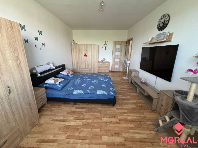 A bedroom in a 3-room apartment with a wood-patterned floor and furniture.