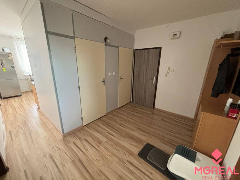 Interior of a 3-room apartment with a wooden decor floor and simple furnishings.