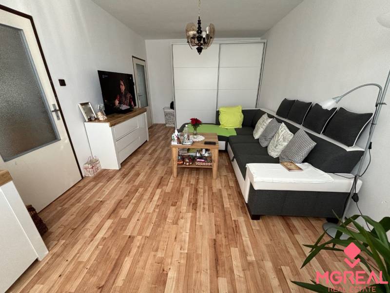 Living room in a three-room apartment with a large sofa and a floor with a wooden decor.