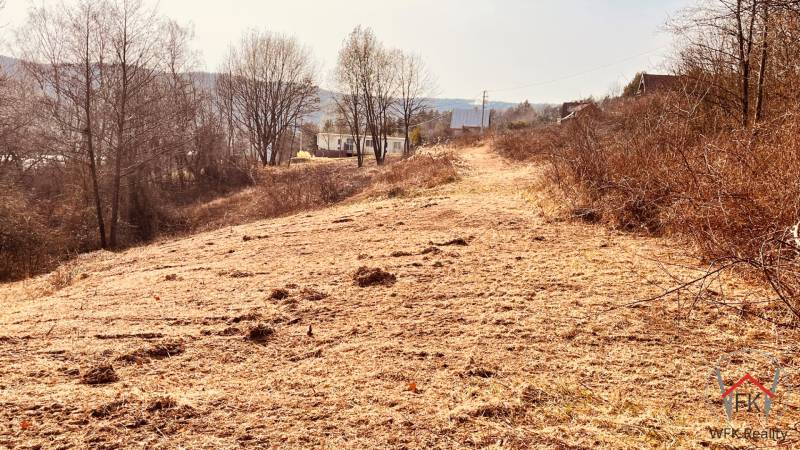 Recreational plots in Nová Kelča with dry grass and trees in the background.