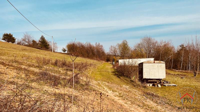 A sloped plot of land with grass cover and a solitary cart in Nová Kelča, recreational plots.