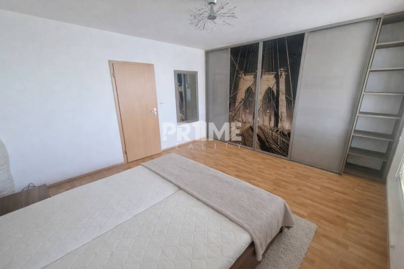 Bedroom in a 2-room apartment with a double bed, wardrobe, and floor with wood decor.