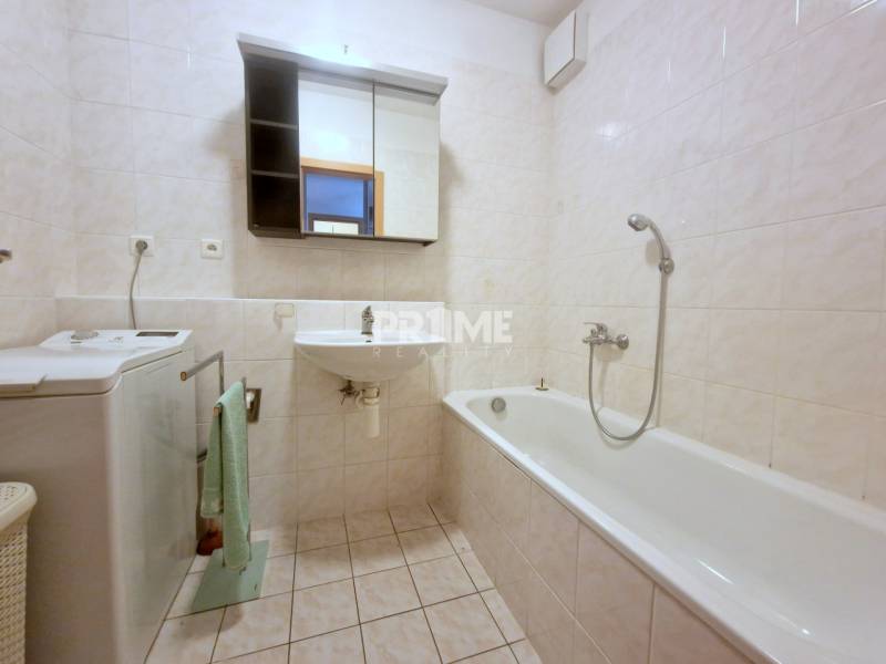Bathroom in a 2-room apartment with a bathtub, washing machine, and mirrored cabinet.