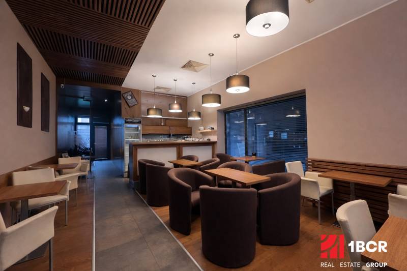 Interior of a commercial space with comfortable armchairs, wooden decor, and modern lighting.
