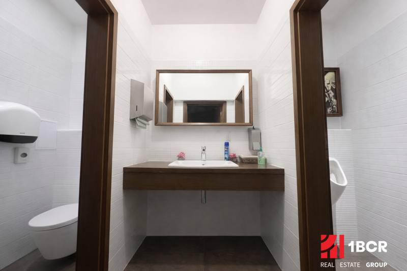 Bathroom with a sink, mirror, and sanitary equipment in commercial premises.