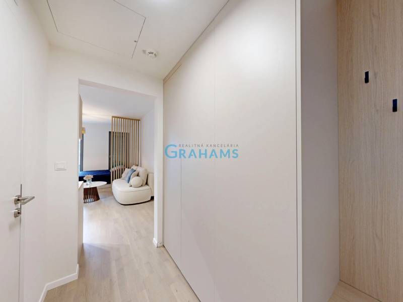 A hallway leading to the living room with decorative seating and wood-patterned flooring.