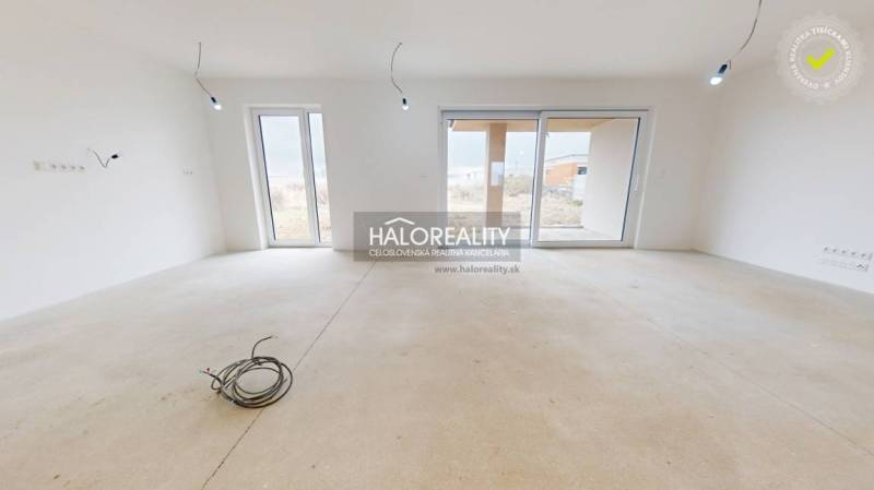 Spacious room with windows and unfinished flooring in a family house.