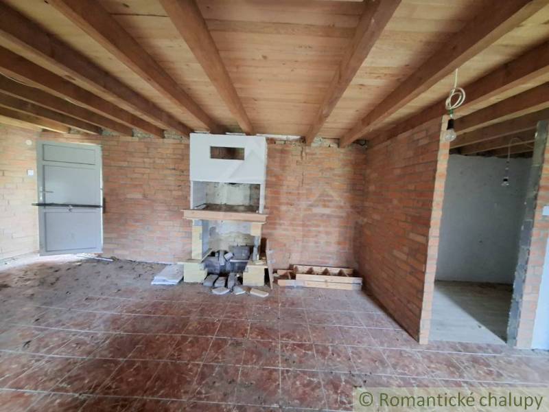 Brick walls, wood-patterned floor, ceiling beams, and a fireplace in the cabin.