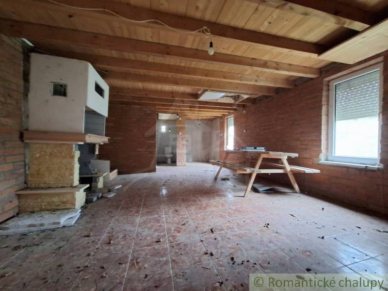 Interior of a cabin with brick walls, a wooden ceiling, and a bench seat.