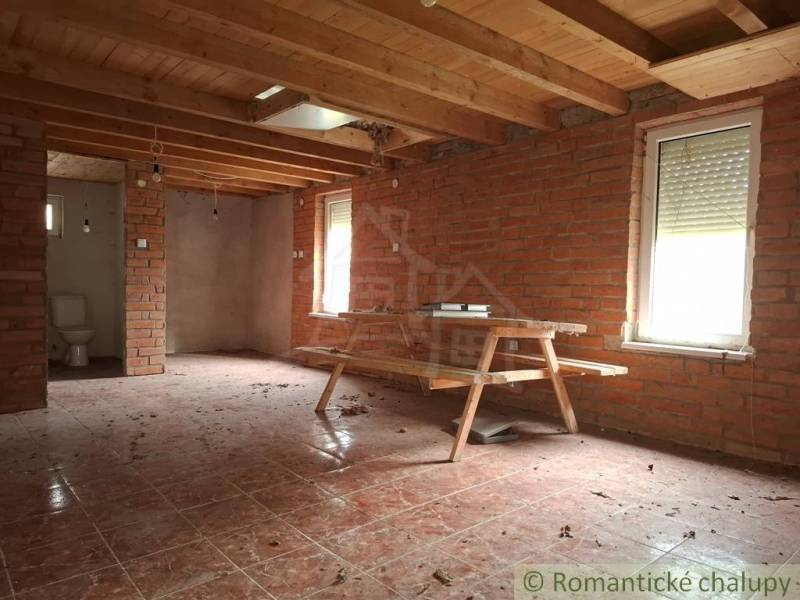 A cottage with brick walls, a wooden decor floor, and simple furniture.
